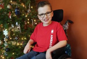 A photo of Zach next to his family's Christmas tree.