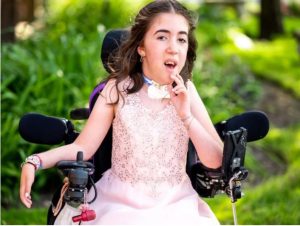 A young girl in a wheelchair with her mouth open.
