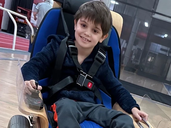 a young boy sitting on a 'volt hockey chair' smiling