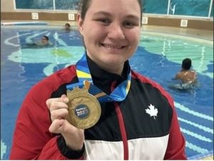 A woman holding a medal in front of a swimming pool.