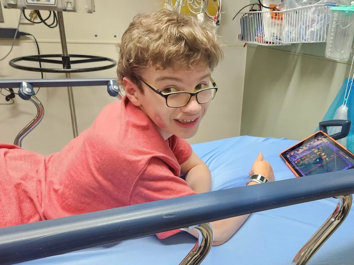 A photo of a young boy sitting on a hospital bed
