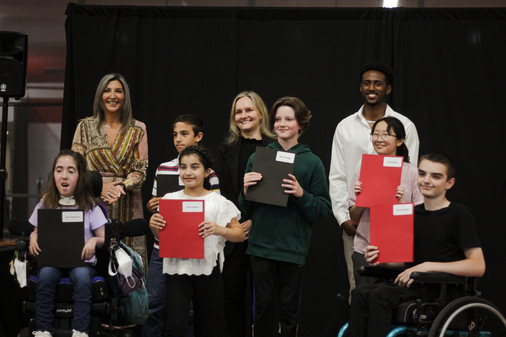 Winner athletes posing with their certificates along with award presenters.