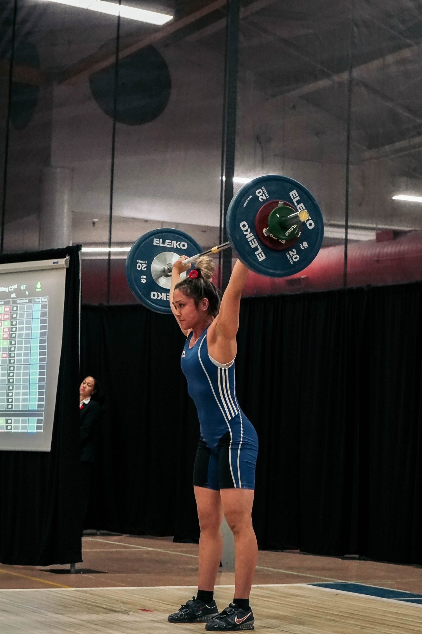 A young woman lifting a barbell on stage